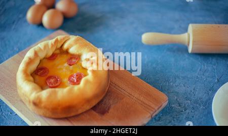 Pizza Mit Tiefem Gericht. Сhicago Pizza 4 Käse, getrocknete Kirschtomaten. Essen auf einem Holzteller, Nudelholz und 4 Eier, Rezept Pie Pizza. Festliches Gebäck auf einem Stockfoto