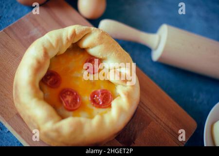 Pizza Mit Tiefem Gericht. Сhicago Pizza 4 Käse, getrocknete Kirschtomaten. Essen auf einem Holzteller, Nudelholz und 4 Eier, Rezept Pie Pizza. Festliches Gebäck auf einem Stockfoto