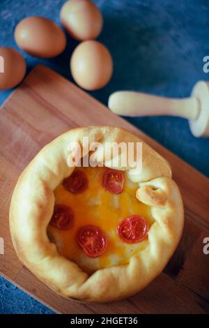 Pizza Mit Tiefem Gericht. Сhicago Pizza 4 Käse, getrocknete Kirschtomaten. Essen auf einem Holzteller, Nudelholz und 4 Eier, Rezept Pie Pizza. Festliches Gebäck auf einem Stockfoto