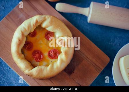 Pizza Mit Tiefem Gericht. Сhicago Pizza 4 Käse, getrocknete Kirschtomaten. Essen auf einem Holzteller, Nudelholz und 4 Eier, Rezept Pie Pizza. Festliches Gebäck auf einem Stockfoto