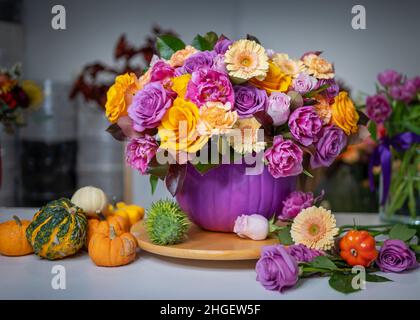 Blumenarrangement mit Rosen und kleinen Kürbissen Stockfoto