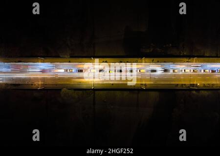 Luftaufnahme der Straße mit schnelllebigen starken Verkehr in der Nacht. Draufsicht auf den städtischen Nahverkehr. Rush Hour mit Bewegung verschwommen Auto Spur Lichter. Stockfoto