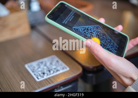 Nahaufnahme der Gäste, die eine Mahlzeit im Restaurant bestellen, während der QR-Code mit dem Mobiltelefon gescannt wird, um ein Online-Menü zu erhalten. Stockfoto