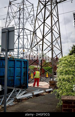 Arbeiter in PSA verwenden oxyde Acetylenbrenner, um beschädigte Teile eines geerdeten Strommasylons auszuschneiden Stockfoto