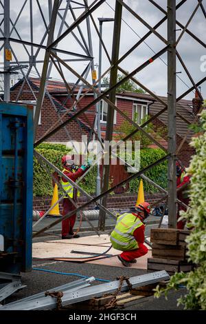 Arbeiter in PSA verwenden oxyde Acetylenbrenner, um beschädigte Teile eines geerdeten Strommasylons auszuschneiden Stockfoto