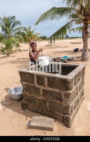 Ein afrikanisches Mädchen nimmt Wasser aus einem Brunnen auf, der unter anderem zum Waschen von Kleidung oder Kochen verwendet wird. Keta Ghana Westafrika 23. Oktober 2021 Stockfoto