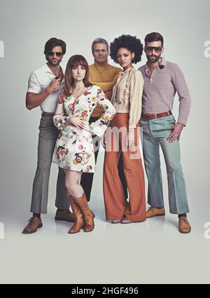 Nichts wie im Stil von 70s. Eine Studioaufnahme einer Gruppe von Menschen, die zusammen stehen, während sie in Retro-70s-Kleidung gekleidet sind. Stockfoto