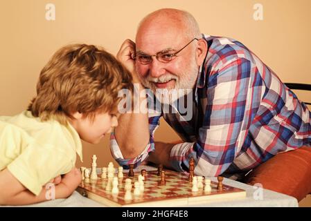 Enkel und Großvater spielen Schach. Kindheit und Gesellschaftsspiele, Familie und Generation Konzept. Stockfoto