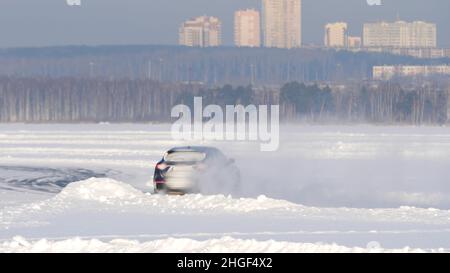 Winterreifen eines Autos auf einer verschneiten Straße. Die Reifen auf der Straße sind an einem Wintertag mit Schnee bedeckt. Das Auto fährt auf einer verschneiten Straße. Stockfoto