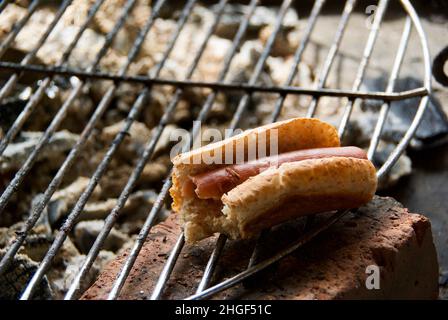 Grillwurst mit Wurstbrot im Freien auf dem Grillgitter. Stockfoto