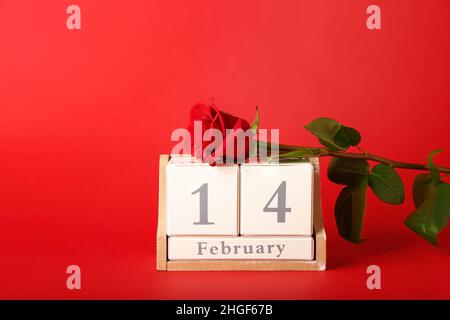 Kalender mit Datum vom 14. Februar und Rose auf farbigem Hintergrund Stockfoto