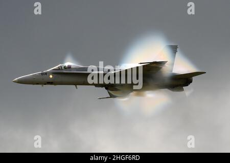 Schockwelle um einen Düsenjäger der Schweizer Luftwaffe McDonnell Douglas Hornet während eines Hochgeschwindigkeitspasses, der sich der Schallgeschwindigkeit bei stürmischem Himmel nähert Stockfoto