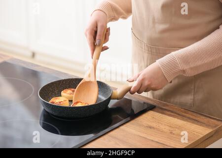 Frau bereitet leckere Hüttenkäse Pfannkuchen in der Küche, Nahaufnahme Stockfoto