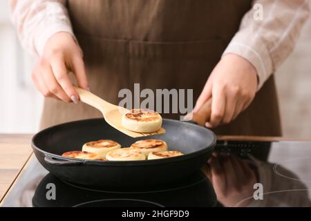 Frau bereitet leckere Hüttenkäse Pfannkuchen in der Küche, Nahaufnahme Stockfoto