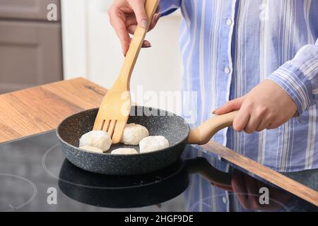 Frau bereitet leckere Hüttenkäse Pfannkuchen in der Küche, Nahaufnahme Stockfoto