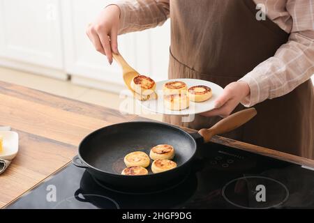 Frau bereitet leckere Hüttenkäse Pfannkuchen in der Küche, Nahaufnahme Stockfoto