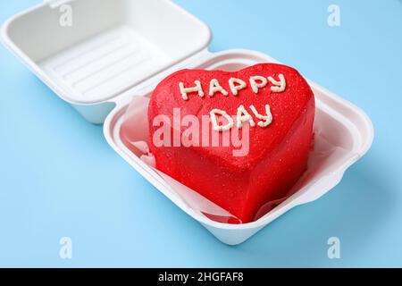 Lunchbox aus Kunststoff mit leckerem Bento-Kuchen auf blauem Hintergrund, Nahaufnahme Stockfoto