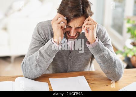 Ich könnte nur weinen. Ein frustrierter Geschäftsmann mit dem Kopf in den Händen über Arbeitsstress. Stockfoto