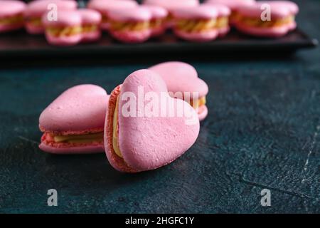 Leckere herzförmige Makronen auf schwarzem Hintergrund Stockfoto