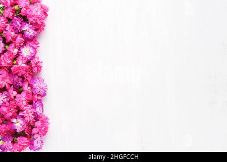 Rosa Nelken Blumen umrandeten auf einem weißen Holzhintergrund. Muttertag, Valentinstag Konzept. Draufsicht, Kopierbereich Stockfoto