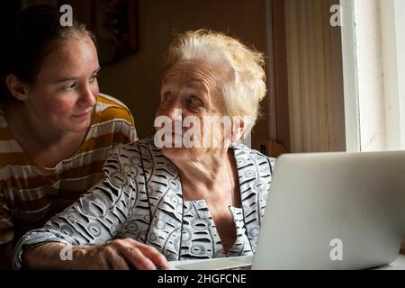 Ein Mädchen lehrt ihre Großmutter, wie man den Computer benutzt. Stockfoto