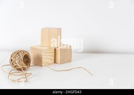 Ein Kein aus Bastelgarn und drei Holzwürfeln auf einer weißen Kommode. Stockfoto