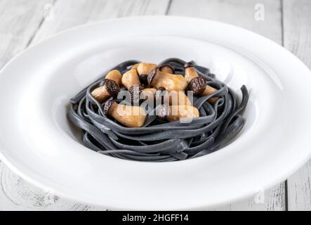 Tintenfisch Tinte Linguine Pasta mit Babypilzen Stockfoto