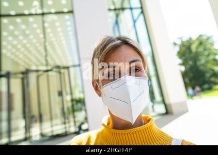 COVID-19 Pandemic Coronavirus Frau in der Stadt Straße trägt KN95 FFP2 Gesichtsmaske Schutz für die Ausbreitung des Krankheitsvirus SARS-CoV-2. Mädchen mit Schutz Stockfoto