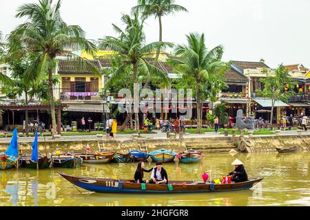 Ein kleines Ausflugsboot mit zwei Passagieren auf dem Thu Bon River in der Altstadt. Stockfoto