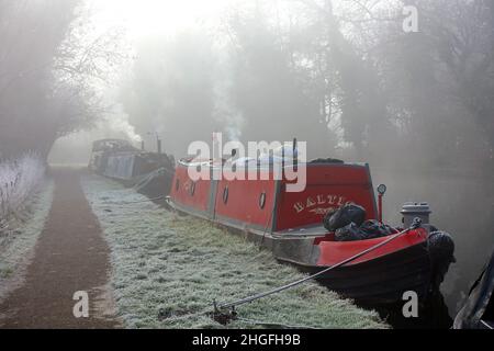 Rauch steigt an einem sehr kalten, frostigen frühen Wintermorgen im Januar aus den Schornsteinen auf den Binnenschiffen am River Gade nahe Watford Stockfoto