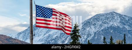 Panorama-Bergkulisse hinter einer amerikanischen Flagge. Sterne und Streifen in Alaska. Stockfoto