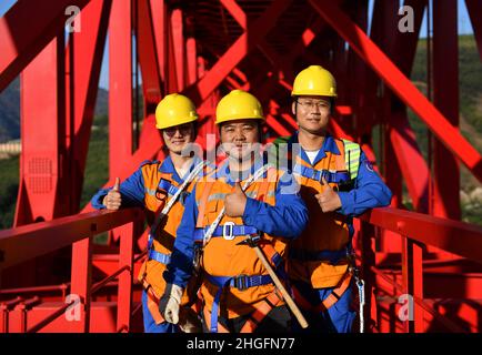(220121) -- YUANJIANG, 21. Januar 2022 (Xinhua) -- Shi Pengbin (C) posiert mit seinen Kollegen auf der Yuanjiang-Hauptbrücke über den Fluss Yuanjiang in der südwestlichen chinesischen Provinz Yunnan für ein Foto, 18. Januar 2022. Shi Pengbin, 28, ist ein Techniker, der für die Wartung der Yuanjiang-Hauptbrücke, einer wichtigen Brücke des China-Laos-Eisenbahnprojekts, verantwortlich ist. Die Yuanjiang-Brücke erstreckt sich über eine Gesamtlänge von 832,2 Metern und besteht aus sechs Brückenpfeilern, wobei der Brückenpier Nr. 3, der höchste Pier, mit 154 Metern Höhe steht. Shi, der seit April 2020 für den Bau der China-Laos-Eisenbahn arbeitet, hat sogar po Stockfoto