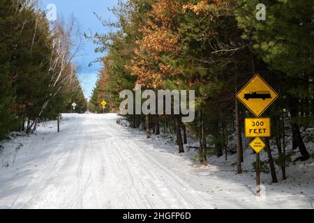 Gepflegter schneebedeckter Schneemobil- und Wanderweg durch einen Wald in Central Minnesota mit gelben Schildern. Paul Bunyan State Trail in Nisswa. Stockfoto