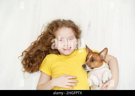 Kleines Mädchen und ihr Freund Welpen spielen auf Holzboden Hintergrund. Stockfoto