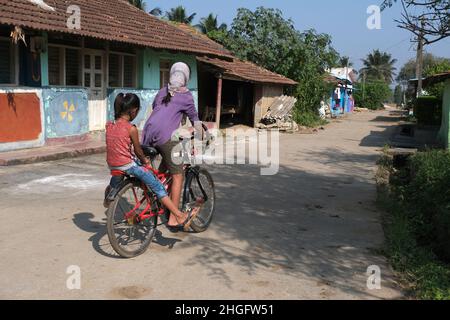 Karnataka, INDIEN 22. Dezember 2021, eine nicht identifizierte indische ländliche Mädchen mit ihrem Fahrrad. Spielzeit, ländliche Straße Stockfoto