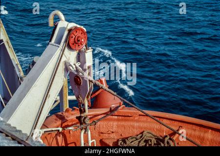 03 04 2019 ein orangefarbenes Rettungsboot, das an der Seite eines Kreuzfahrtschiffs über ruhigen grauen Meeren hängt Stockfoto