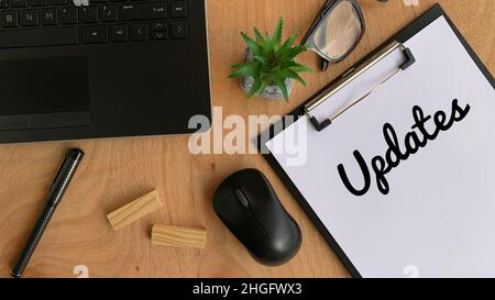 Aktualisiert das Wort, das auf ein Stück Papier geschrieben wurde. Mit Brille, Maus, Holzblöcken, Pflanze, Laptop und braunem Tischhintergrund. Geschäftskonzept Stockfoto