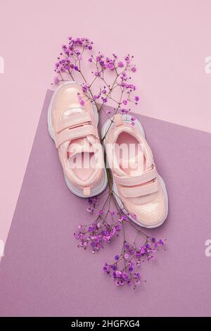 Sportschuhe, Turnschuhe und natürliche Blumen auf rosa violettem Hintergrund. Frühjahrssport-Konzept. Draufsicht Flat Lay. Stockfoto