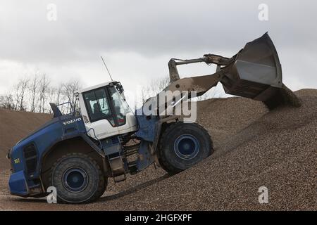 Weeze, Deutschland. 20th Januar 2022. Ein Bagger schaufelt Kies auf einen Vorratsstapel bei der Kiesfabrik Weeze Kies GmbH & Co.KG der Hülskens Holding. Quelle: Oliver Berg/dpa/Alamy Live News Stockfoto