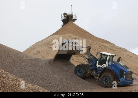 Weeze, Deutschland. 20th Januar 2022. Ein Bagger schaufelt Kies auf einen Vorratsstapel bei der Kiesfabrik Weeze Kies GmbH & Co.KG der Hülskens Holding. Quelle: Oliver Berg/dpa/Alamy Live News Stockfoto