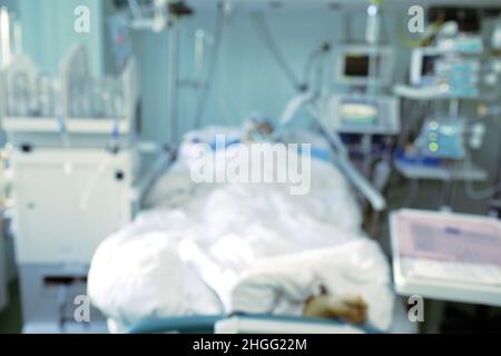 Verschwommene Silhouette eines bewusstlosen Mannes im Krankenhausbett, unfokussierter Hintergrund. Stockfoto