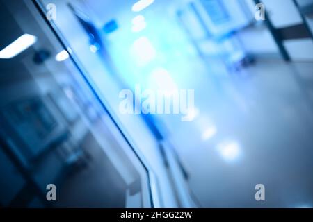 Verschwommener Laborgang mit Überwachungsfenstern und beleuchteter Tür am Ende, unfokussierter Hintergrund. Stockfoto