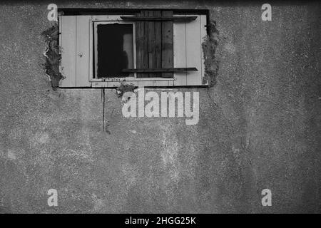 Kleines Fenster in einer Betonwand, halb vermauert. Stockfoto