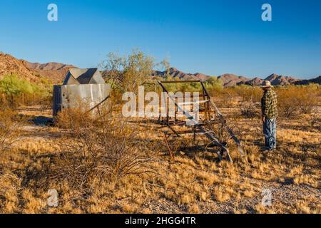 Wanderer am eingestürzten Windpumpenmast, Wasserbehälter am Hazen Well, ehemalige Ranch in Margies Cove, Maricopa Mtns, Sonoran Desert National Monument, USA Stockfoto