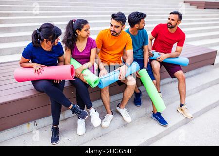 Lustige östliche ethnische Menschen trainieren gemeinsam im Freien Stockfoto