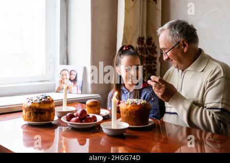 Glücklicher älterer Mann Granfather Vorbereitung für Ostern mit Enkelin. Bemalte farbige Eier für Ostern Stockfoto