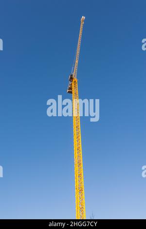 Hoher gelber Baukran gegen klaren blauen Himmel Stockfoto