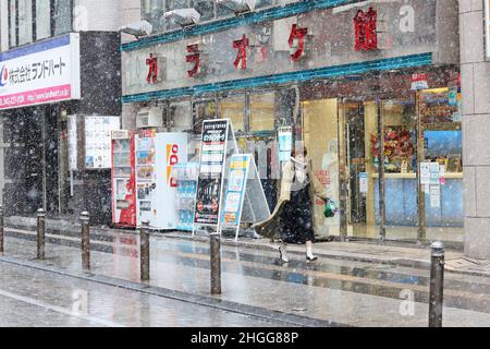 Eine Straße in Chiba City, Japan mit einem Karaoke Kan Karaoke-Zentrum an einem verschneiten Tag. Stockfoto