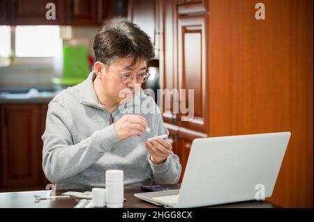 Mann mittleren Alters, der zu Hause einen schnellen Antigen-Test auf COVID-19 macht. Stockfoto