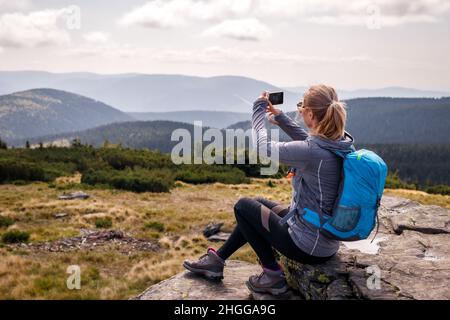Wandererin, die mit ihrem Smartphone Bilder von Bergen fotografiert. Wanderurlaub in der Natur Stockfoto